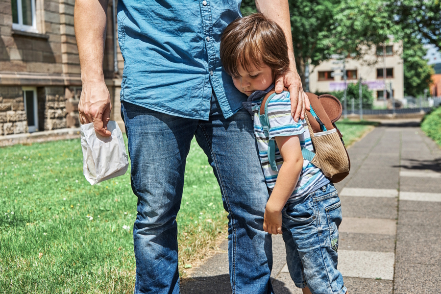 boy standing next to dad's leg feeling shy
