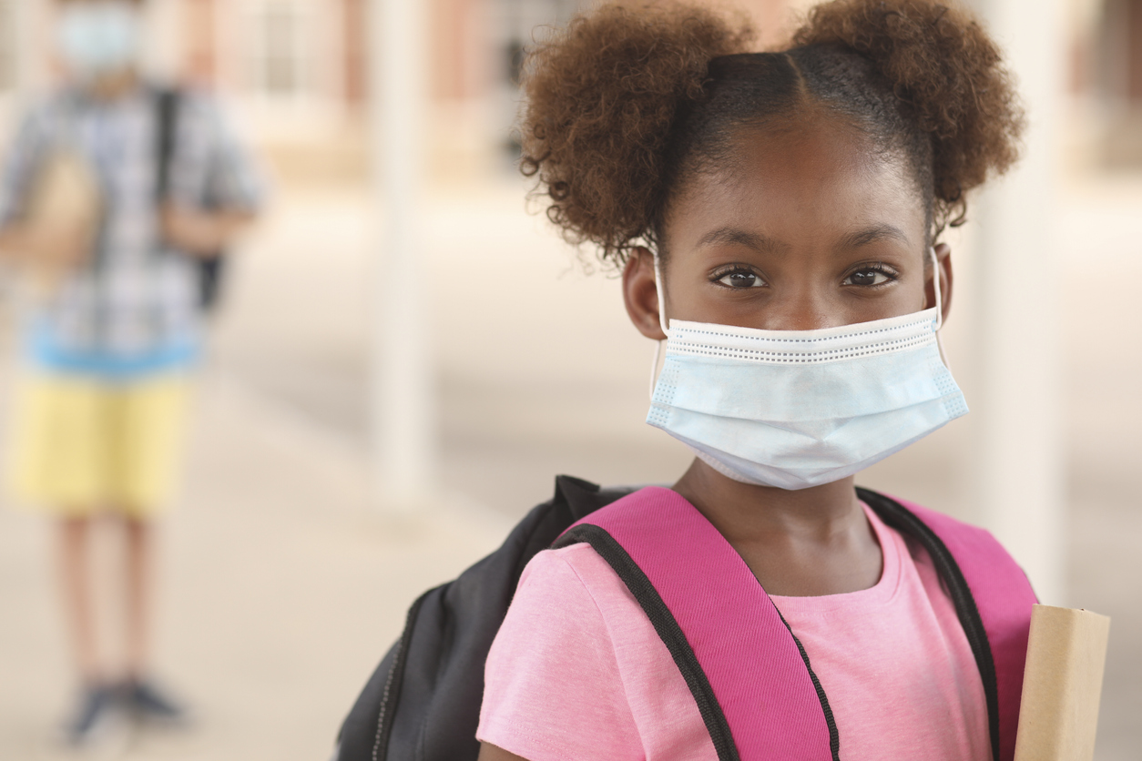 Young girl wearing a surgical mask and a school backpack
