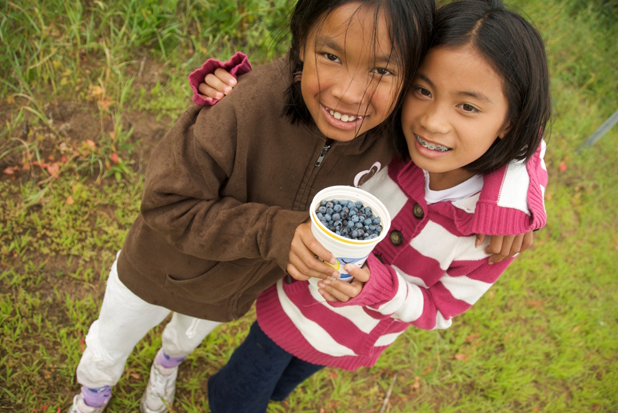 Two girls holding a container of blueberries