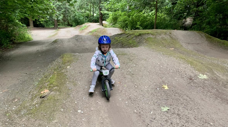 A little girl riding a bike on a pump track, a great outing for a toddler or preschooler.