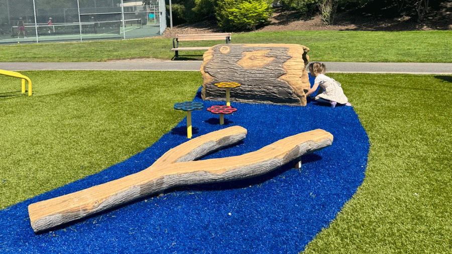 young girl climbing through a log tunnel at the new Hidden Valley Park Playground in Bellevue