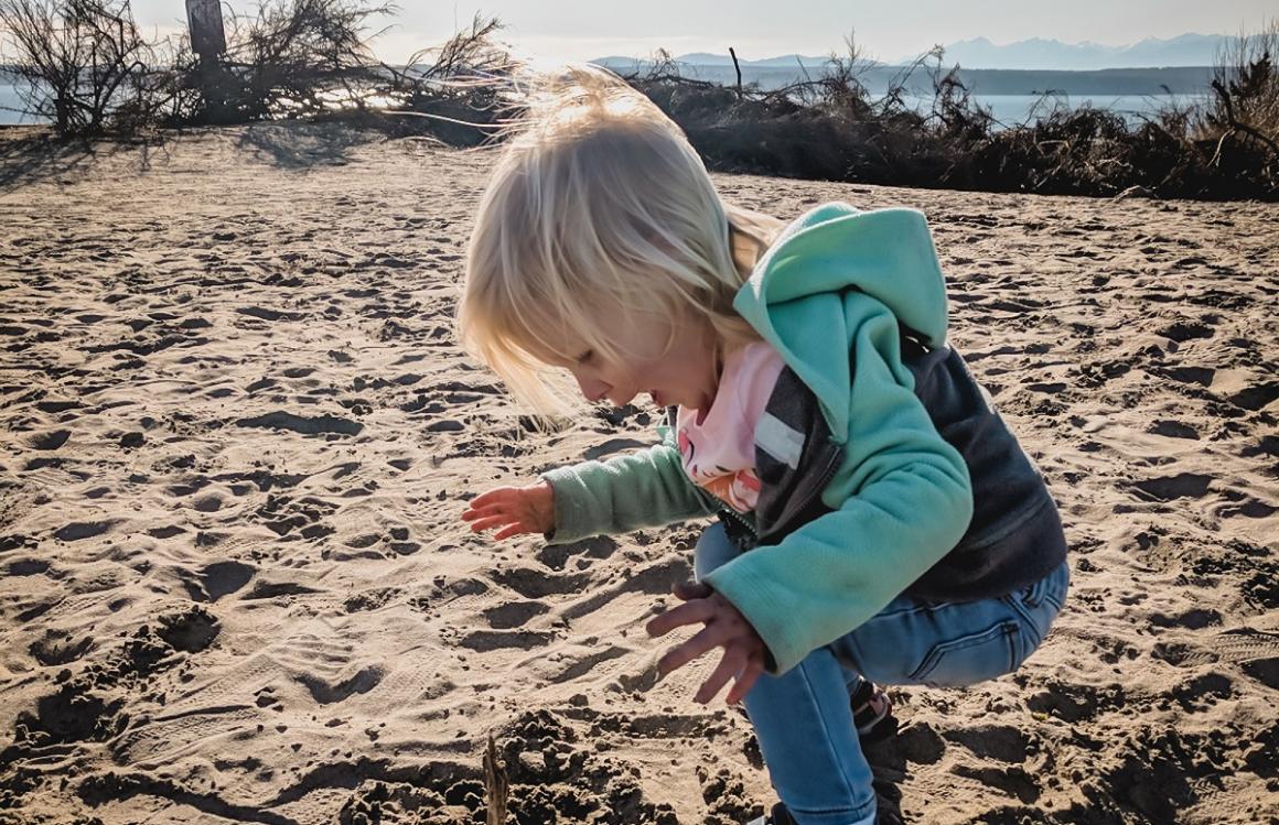 Girl playing in the sand on the bluff at Seattle’s Discovery Park best biggest parks around Seattle