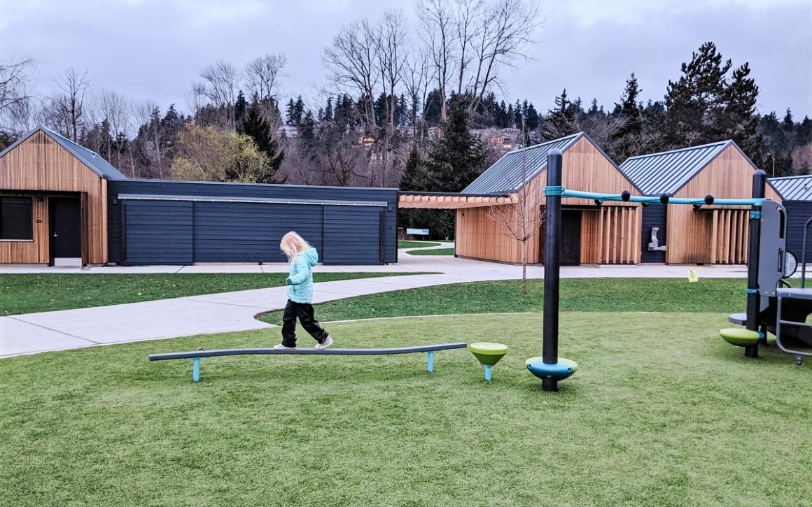 Girl balancing on a play element at Juanita Beach Park's new playground in Kirkland near Seattle