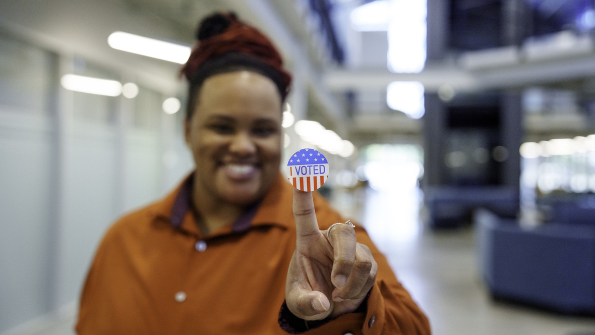 woman holding up a sticker that says I voted