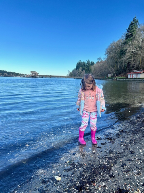 A girl walking on the shore in pink boots at Dockton playground