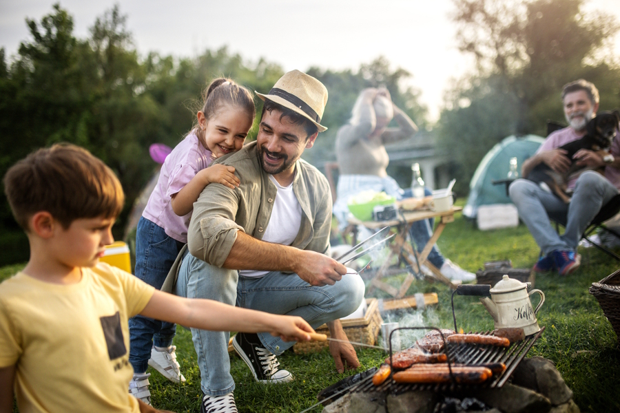 family camping and having fun together, son helping make food over campfire