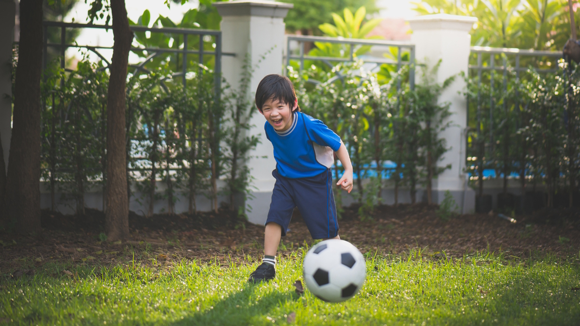 boy kicking a soccer ball in a backyard party