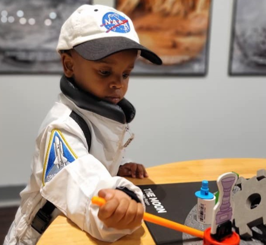 Young boy playing at the Mission to the Moon exhibit at KiDiMu