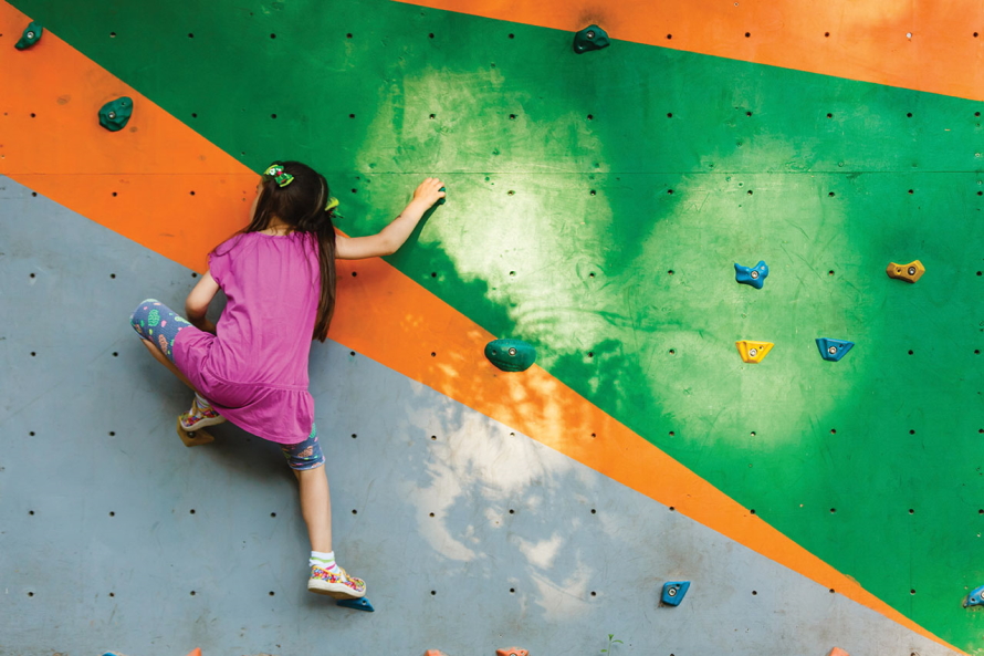 Young girl climbing a rock wall