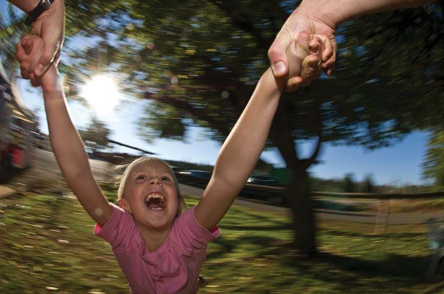 Young girl being swung around in a circle with a big smiling and laughing