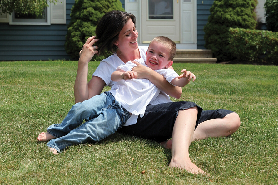 Mother holding son and playing int he grass