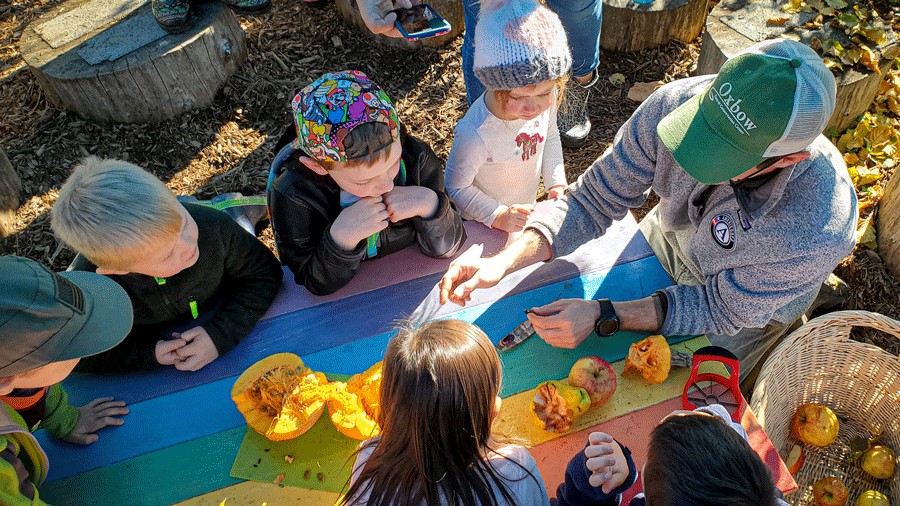 Kids around a table learning about seeds at Oxbow Farm, a Seattle-area teaching garden