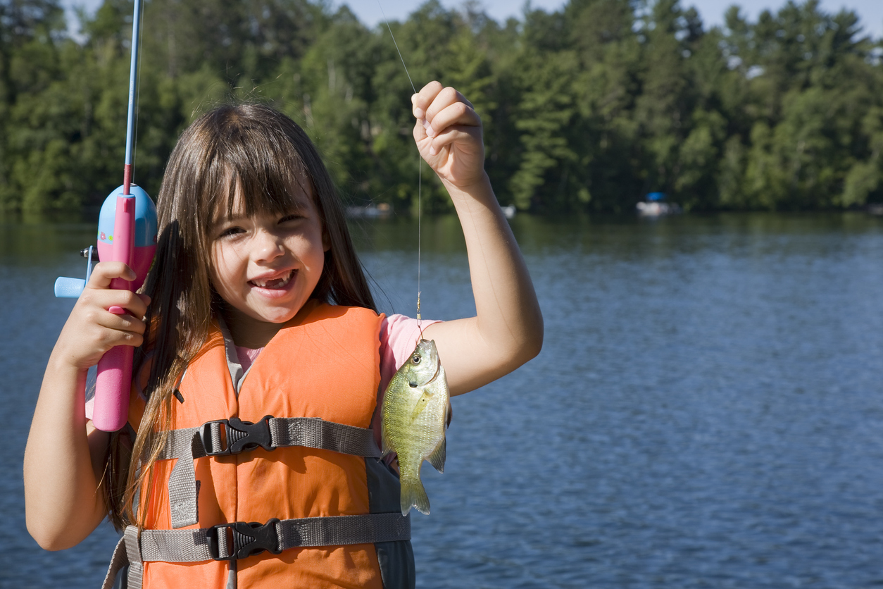 girl holding up fish fishing wearing life jacket where to go fishing with kids near seattle