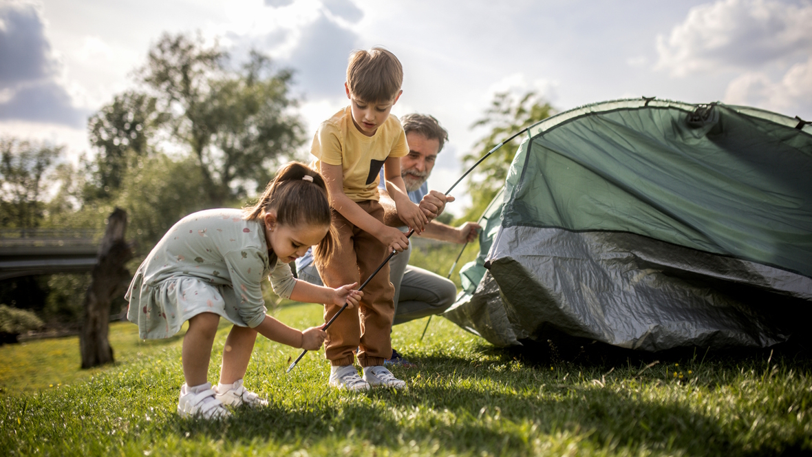 kids helping to set up a camping tent in the grass