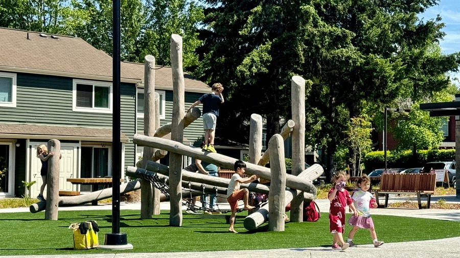 Young kids climb on a log structure at Pathways Park, the largest playground in Seattle