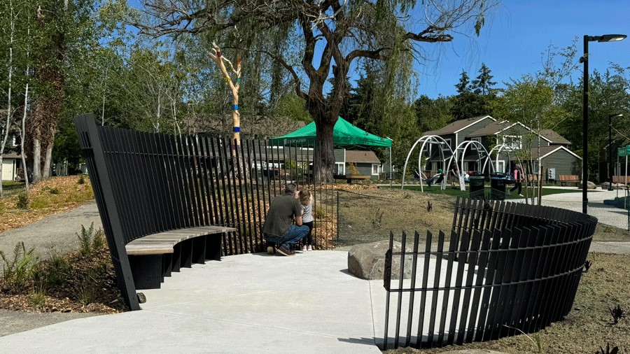 Young girl and her father peek through the slats at Pathway Park’s Nest for a sensory break from playtime