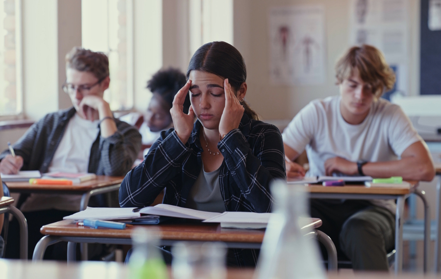 teen girl in a school classroom with a headache