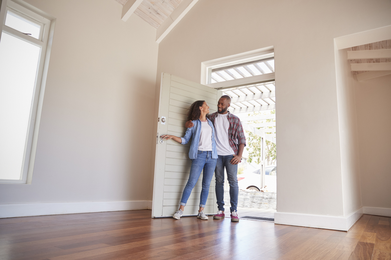 happy smiling couple opening the door to their new home