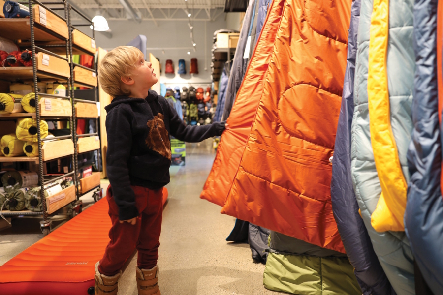 little boy looking at sleeping bags in a store backpacking with kids