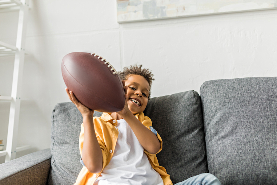 boy holding a football at home smiling