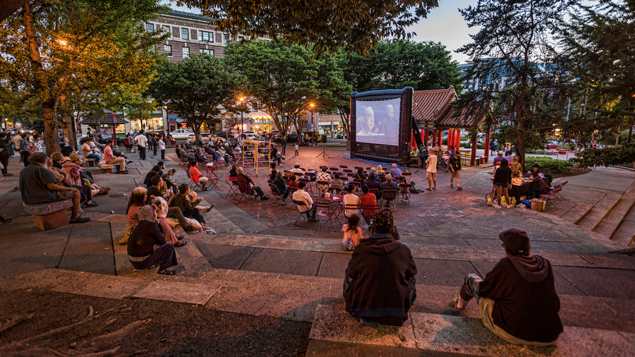 Outdoor movies in Seattle play at different parks, including Hing Hay Park where a crowd gathers to watch a movie