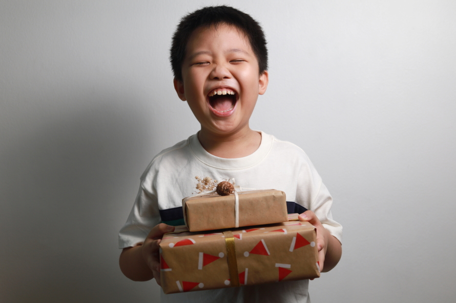 Young boy holding two packages with a big smile and eyes closed