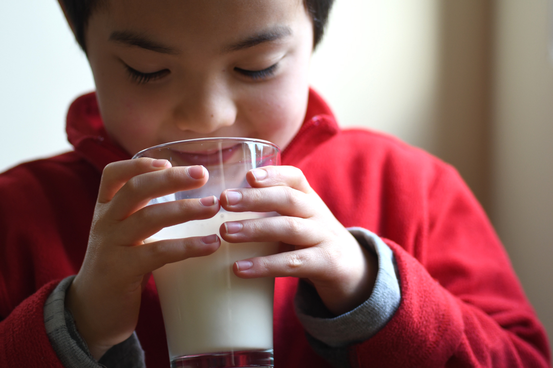 A boy sips a glass of soy milk from Northwest Tofu