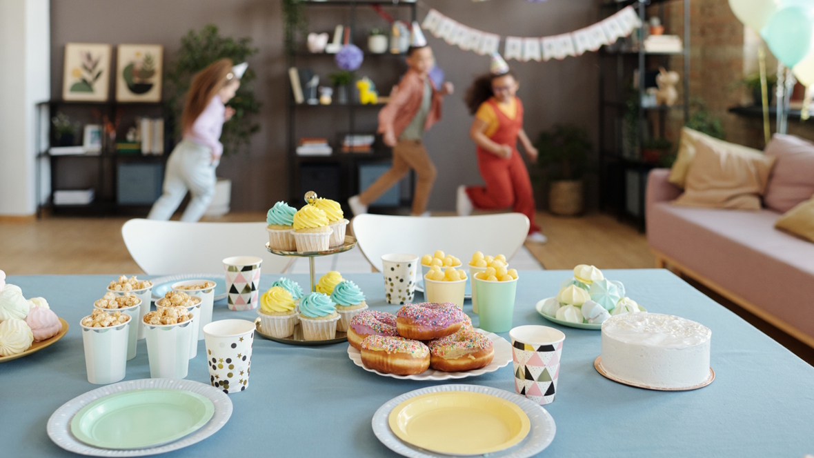 kids running around at a birthday party behind a table covered with birthday party treats