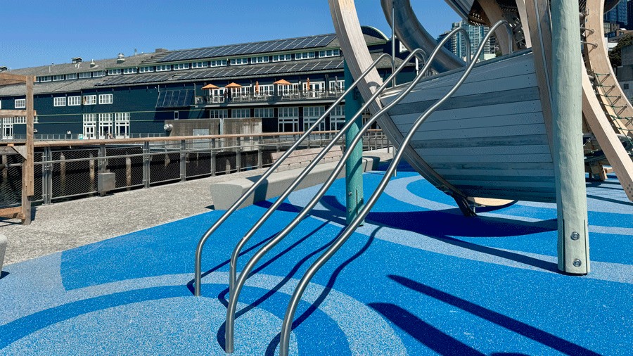 rail bars at the Pier 58 playground, attached to a climbing wall, with bright blue rubber surfacing beneath