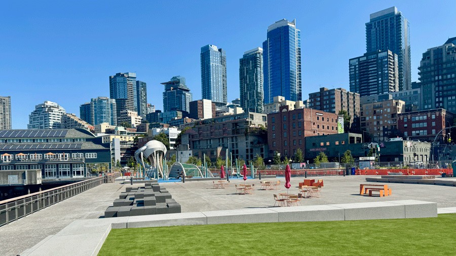 view of Pier 58 open space and green turf lawn with the Seattle skyline