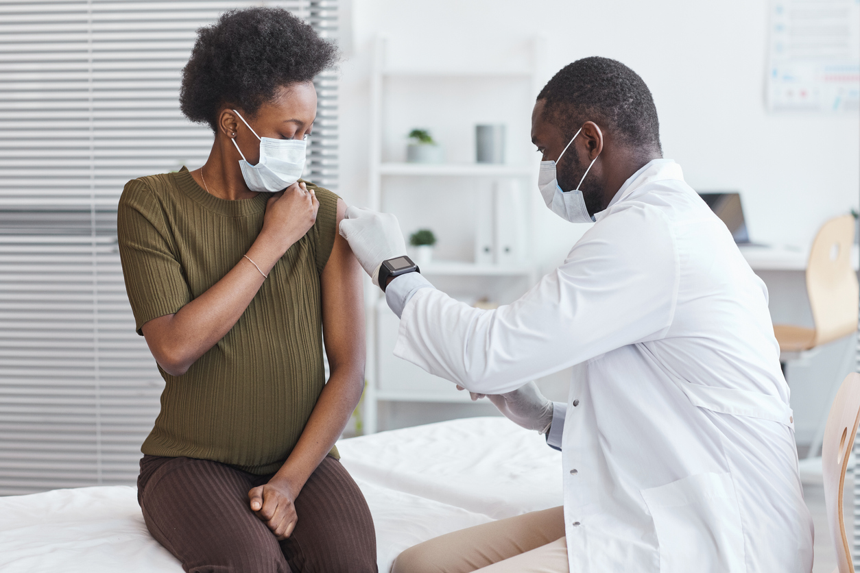 Doctor in white coat vaccinating pregnant woman during a hospital visit