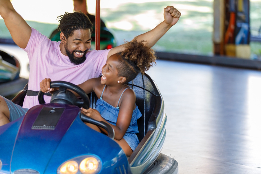 Girl and her dad in a blue bumper car at a theme park