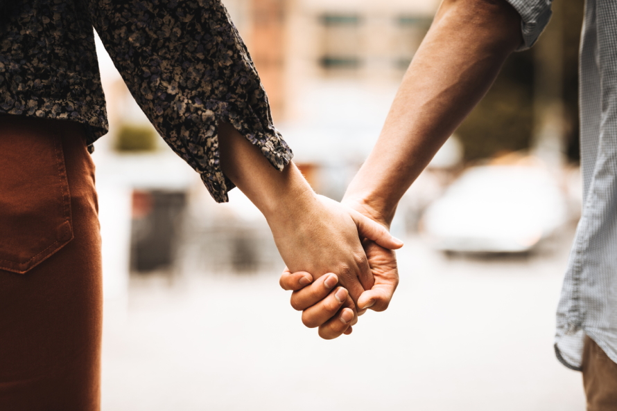 Two adults holding hands on a street