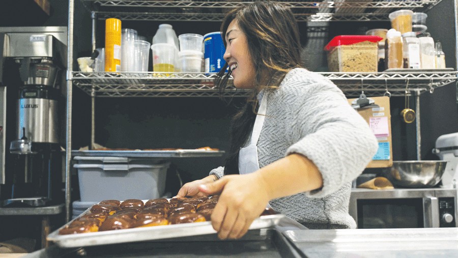 Pastry chef with a tray of fresh-baked doughnuts at Raised Doughnuts in Seattle