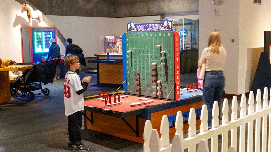 boy playing oversize Battleship at Toytopia a traveling exhibition on display at Washington State History Museum