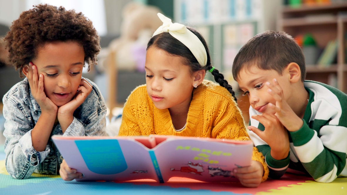 three kids on the floor reading a book together