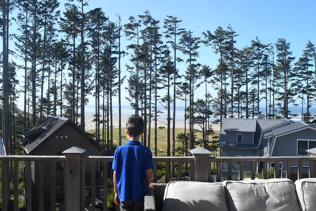 A boy looks out at the view of the Pacific Ocean and the beach from a rental home at Seabrook, Washington, a popular vacation destination for Seattle families