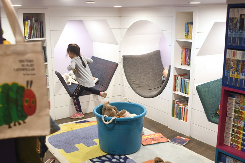 A girl hopes into an alcove in the kids' section of Joies de Livres, Seabrook’s bookstore