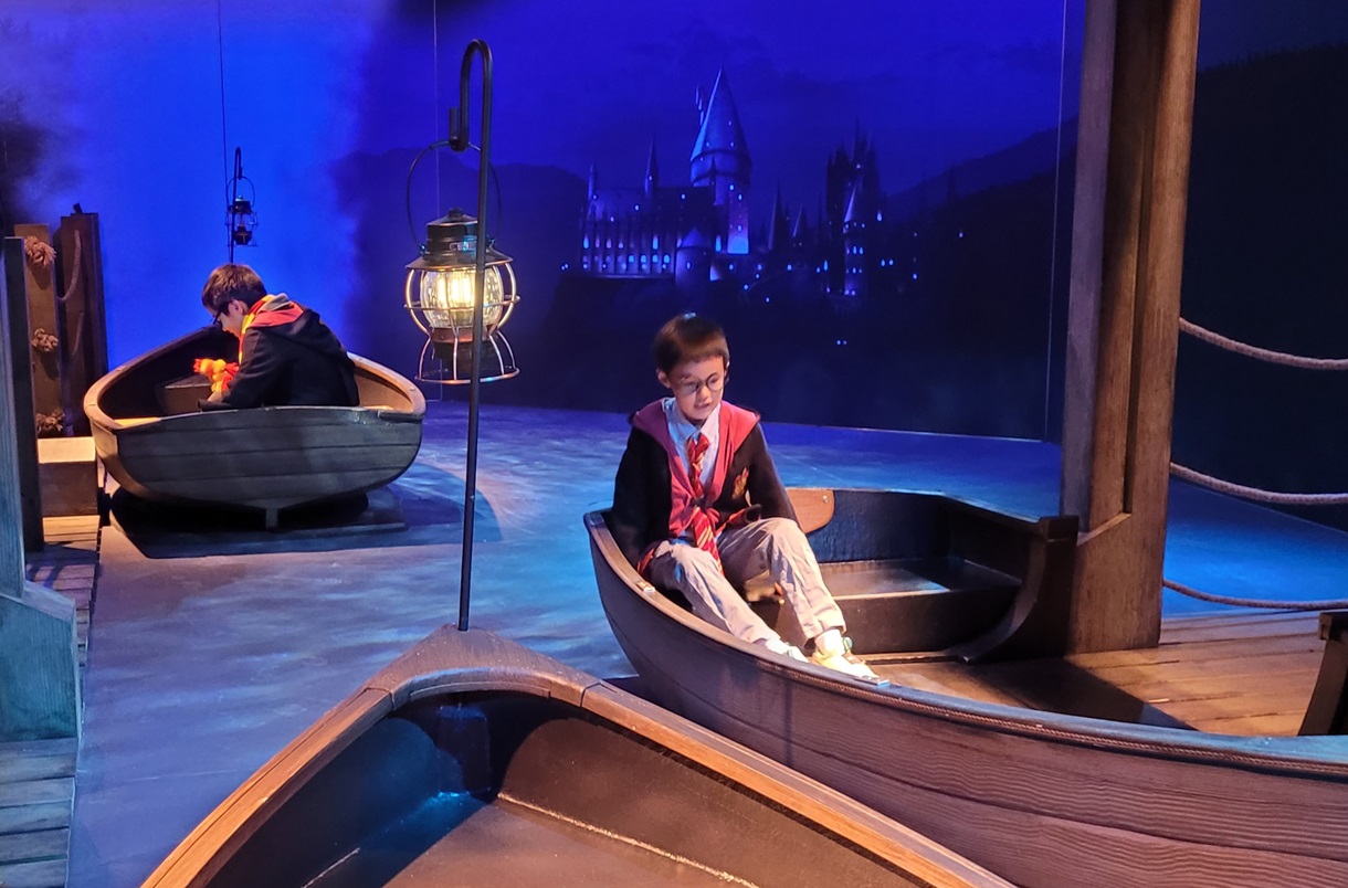 At Harry Potter: Magic at Play in Seattle boys cross the lake in boats toward Hogwarts