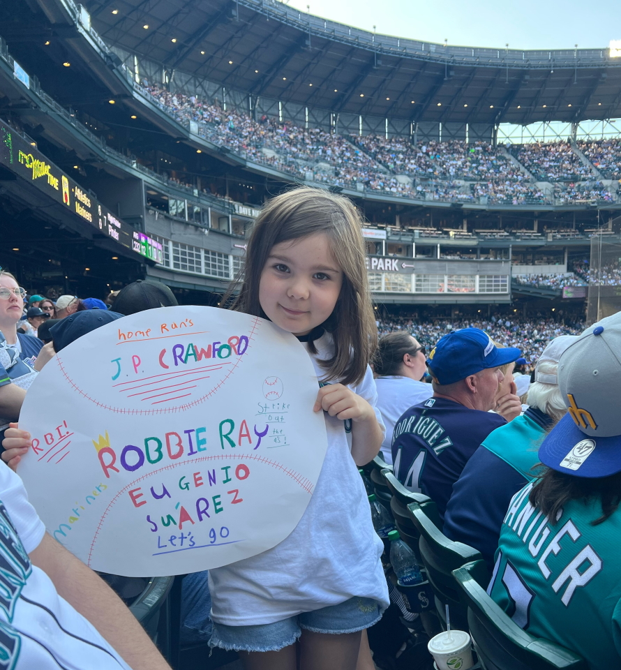 Young girl holding a homemade sign at a Mariner's baseball game