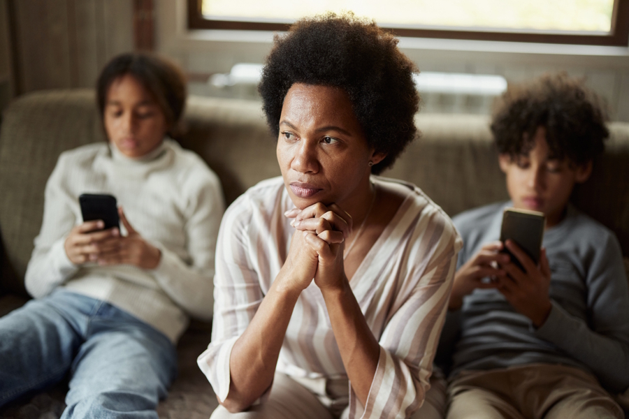 mom sitting on a couch with two teens using phones