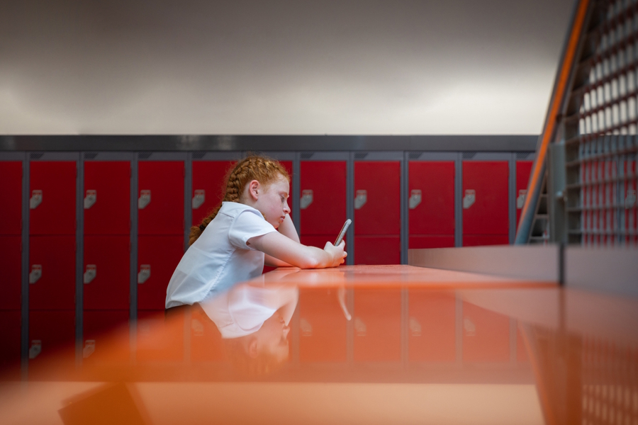 child on their phone alone at school