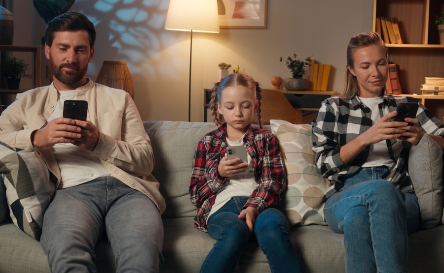 family sitting on couch each looking at their own cell phone