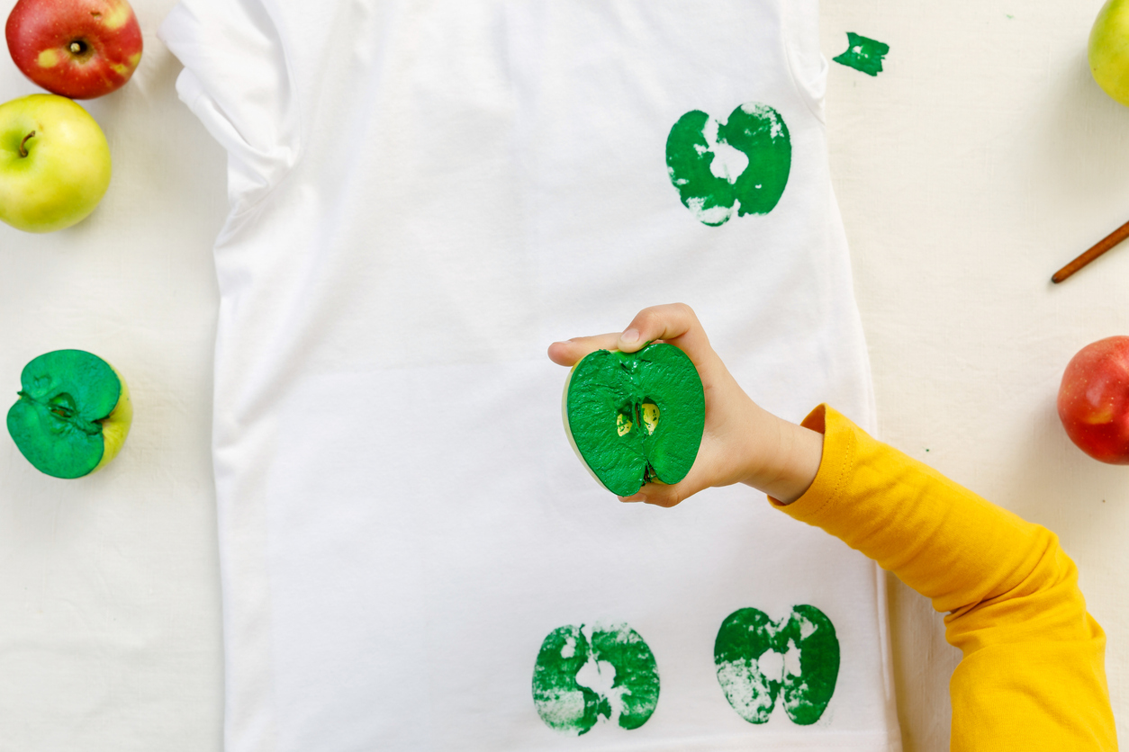 a child uses an apple to make prints