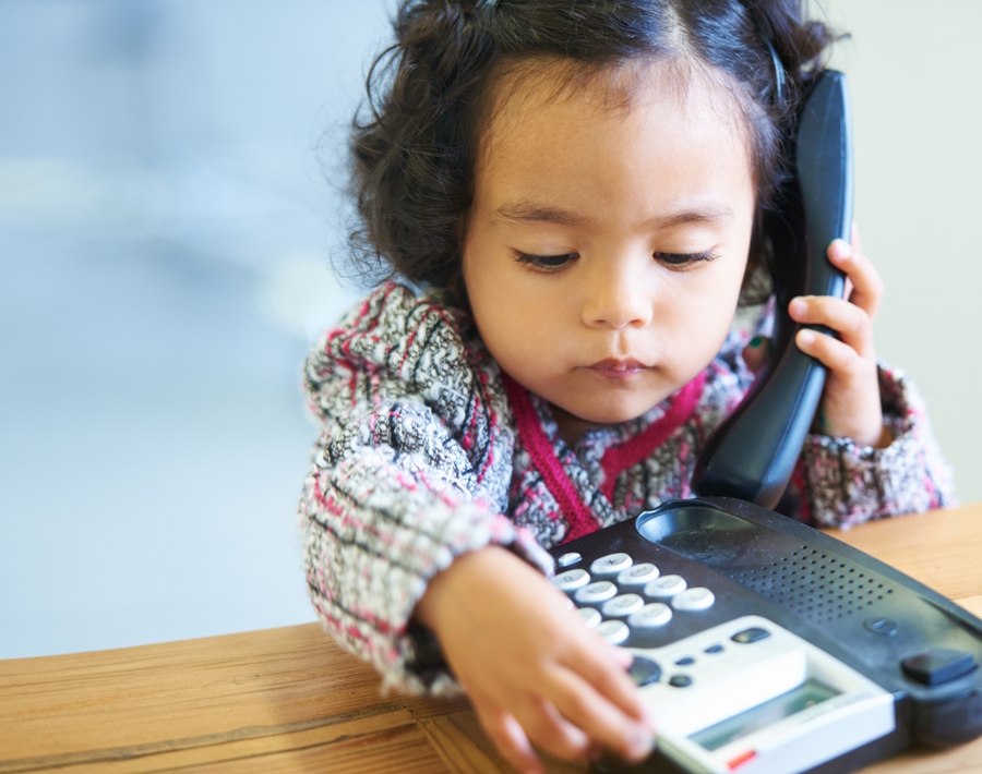 little girl dialing a landline phone