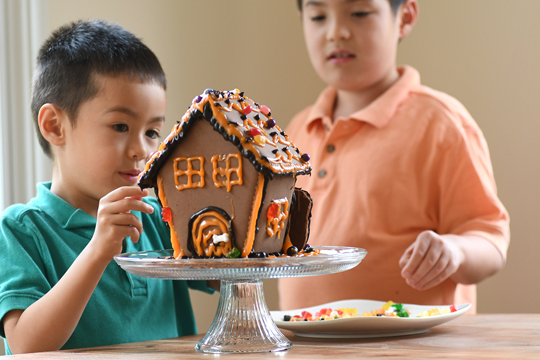 boys making a gingerbread house with halloween decorations