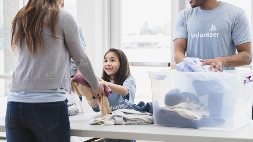 Child handing out clothing and spreading kindness