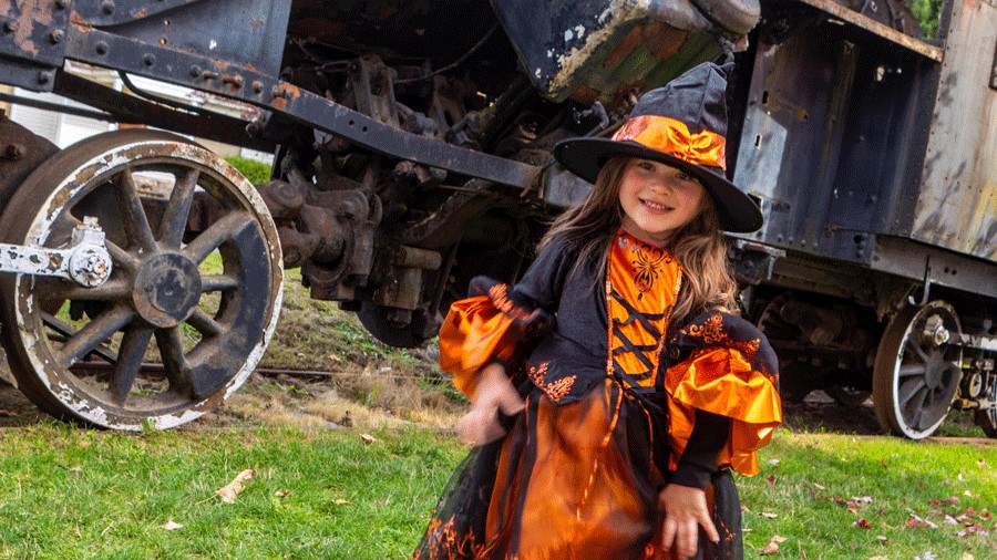 Young girl in a Halloween costume in front of the Family Halloween Train near Seattle