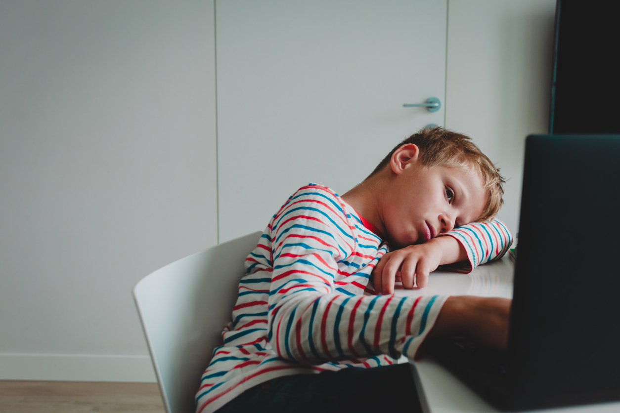 discouraged boy slumped on his desk in front of a computer