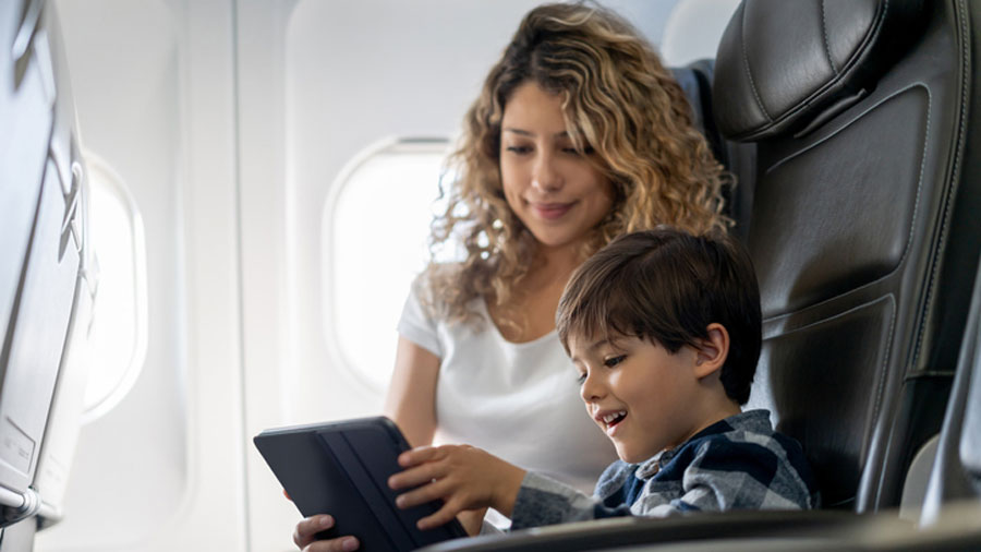mom and son looking at a tablet on an airplane
